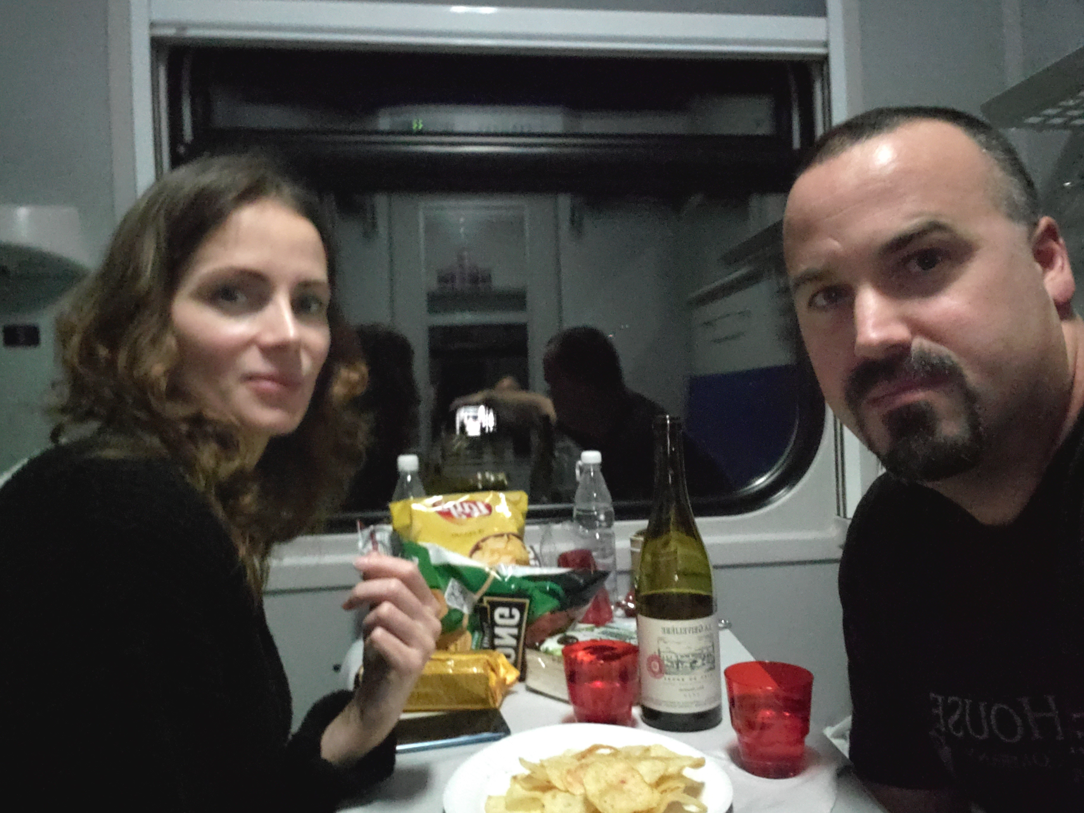 me and my wife with food and drinks in front of window on a train