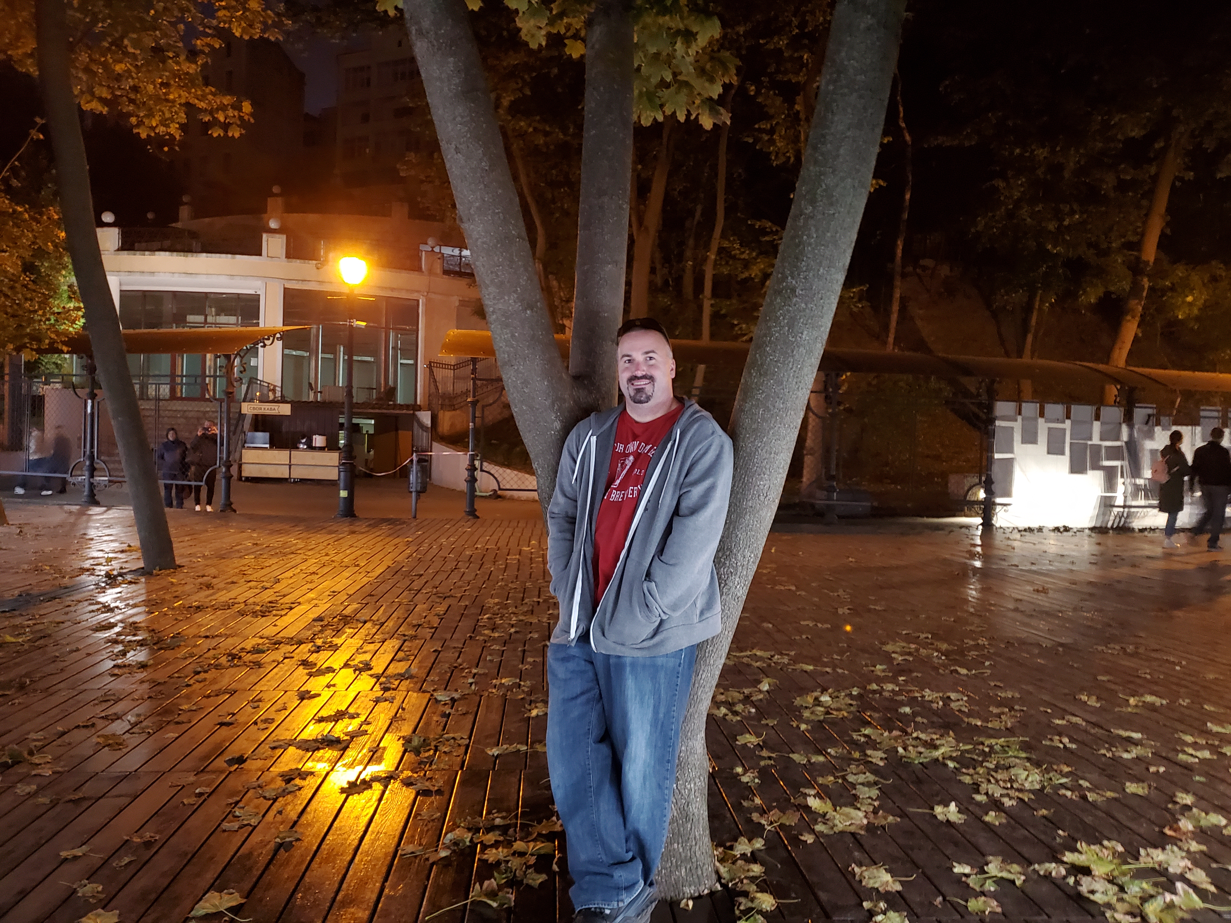 me leaning on a tree on a deck in Kyiv at night